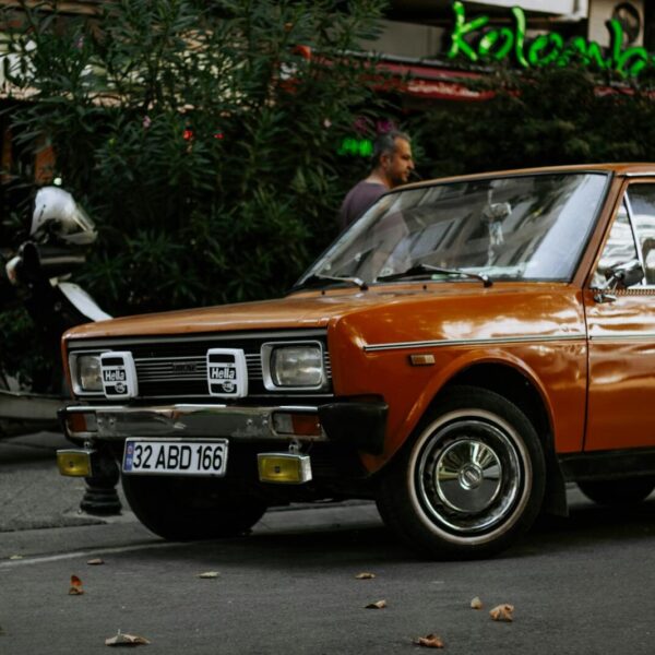 Classic orange car parked on a bustling Istanbul street with a nostalgic ambiance.
