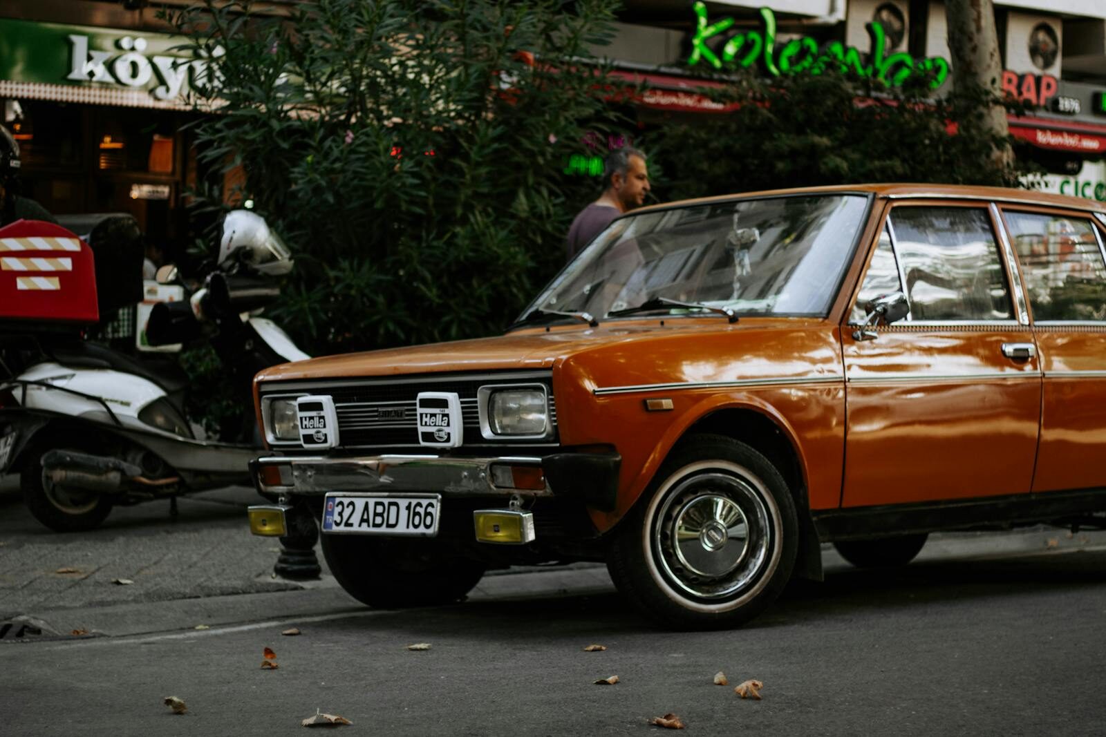 Classic orange car parked on a bustling Istanbul street with a nostalgic ambiance.