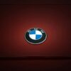 Close-up of BMW emblem on a glossy red vehicle surface, emphasizing modern design.