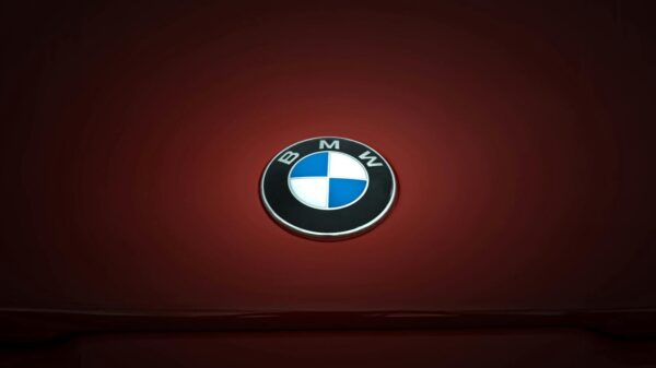 Close-up of BMW emblem on a glossy red vehicle surface, emphasizing modern design.