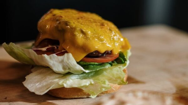 Close-up of a tasty cheeseburger with lettuce, tomato, and cheese on a wooden surface.