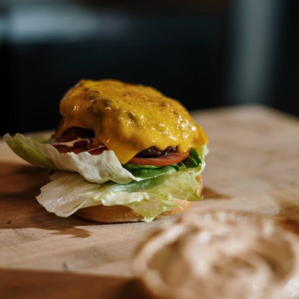 Close-up of a tasty cheeseburger with lettuce, tomato, and cheese on a wooden surface.