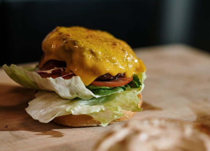 Close-up of a tasty cheeseburger with lettuce, tomato, and cheese on a wooden surface.
