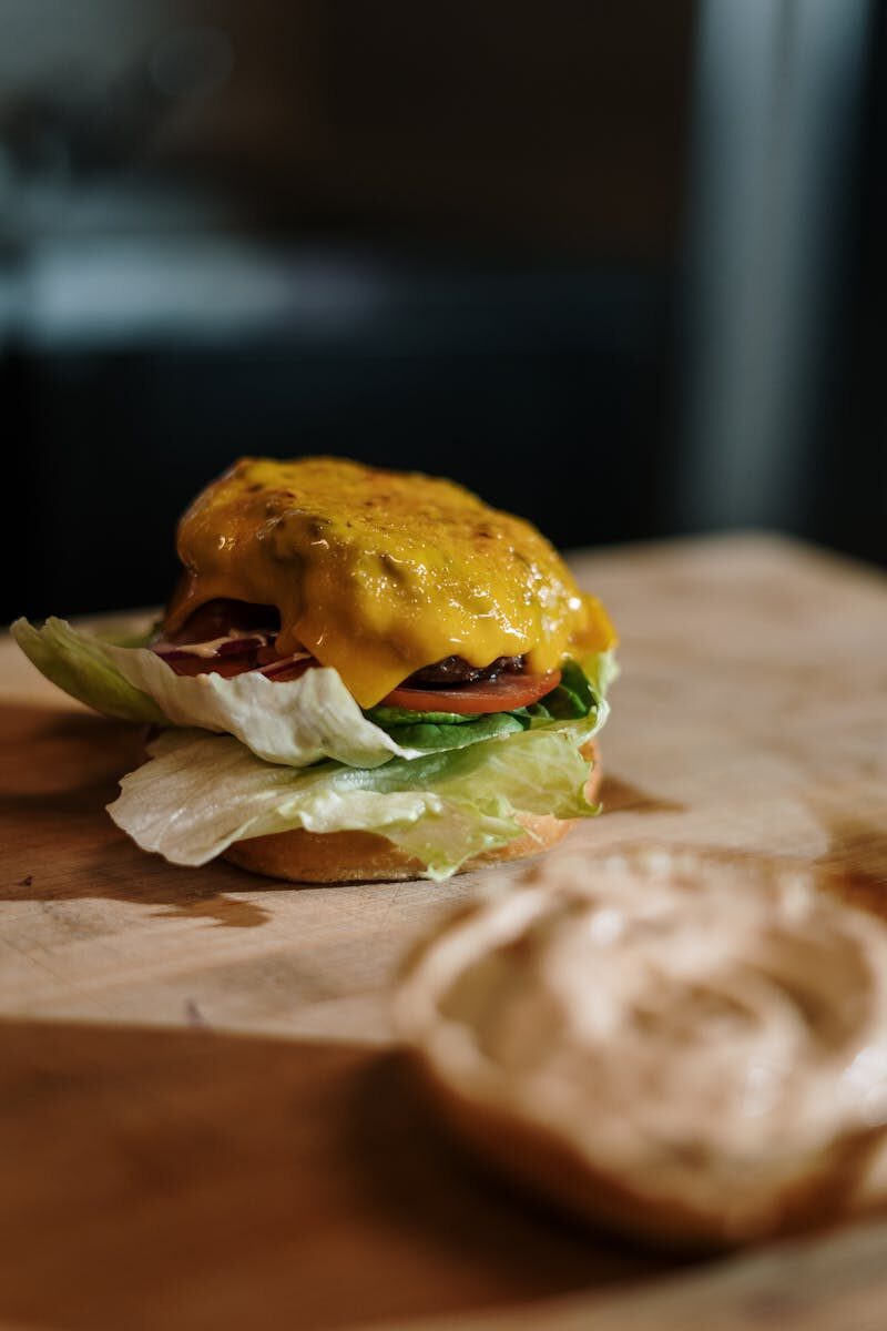 Close-up of a tasty cheeseburger with lettuce, tomato, and cheese on a wooden surface.