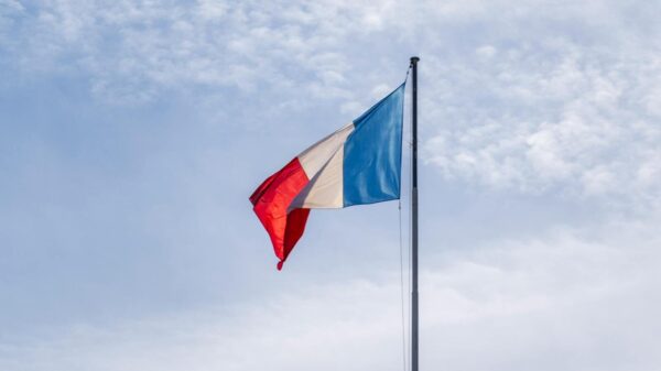 The French national flag waving against a blue sky in Paris, France.