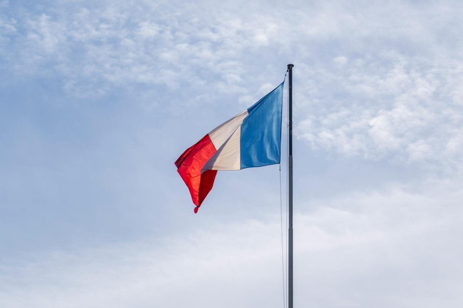 The French national flag waving against a blue sky in Paris, France.