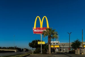 McDonald's golden arches sign with palm tree in front of a clear blue sky in Houston, TX.