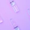 From above small glass vials with vaccine against COVID 19 arranged on purple background