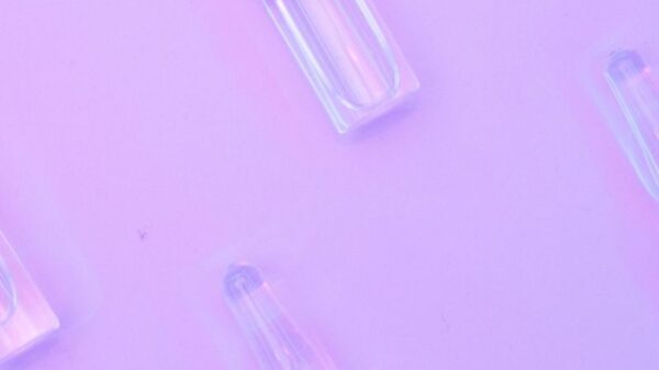 From above small glass vials with vaccine against COVID 19 arranged on purple background