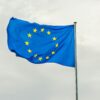 The European Union flag gracefully waving on a flagpole against a cloudy sky in Strasbourg, France.