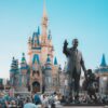 View of the iconic Cinderella Castle at Walt Disney World in Orlando, Florida, with crowd and statue.