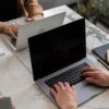 Two people working on laptops in a modern office setting, showcasing teamwork and productivity.