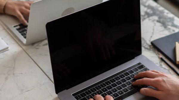 Two people working on laptops in a modern office setting, showcasing teamwork and productivity.