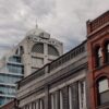 Cityscape with Oracle building in Kitchener, showcasing diverse architectural styles under an overcast sky.