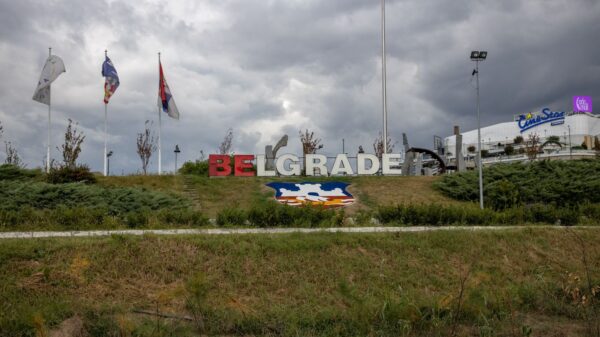 Large Belgrade sign in a park setting with flags on a cloudy day, Serbia