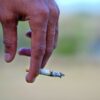 Detailed image of a hand holding a cigarette, signifying smoking habits and health risks.