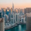 Aerial view of Dubai Marina with skyscrapers at sunset reflecting in the water.
