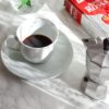 Elegant coffee scene with Lavazza packaging and floral decor on a marble tabletop.