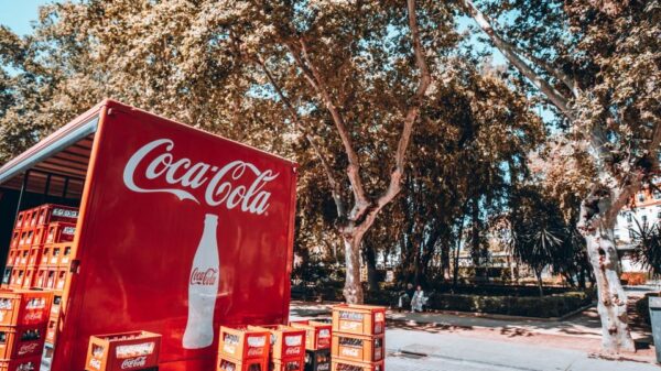 Coca-Cola truck unloading crates on a sunny street in Seville, Spain.