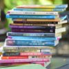 A colorful pile of self-help and business books arranged outdoors, showcasing various titles and themes.