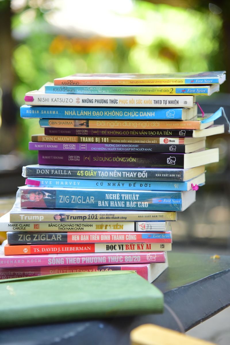 A colorful pile of self-help and business books arranged outdoors, showcasing various titles and themes.