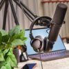 A modern podcast studio setup with a microphone, headphones, and laptop, ideal for media production and online broadcasting.