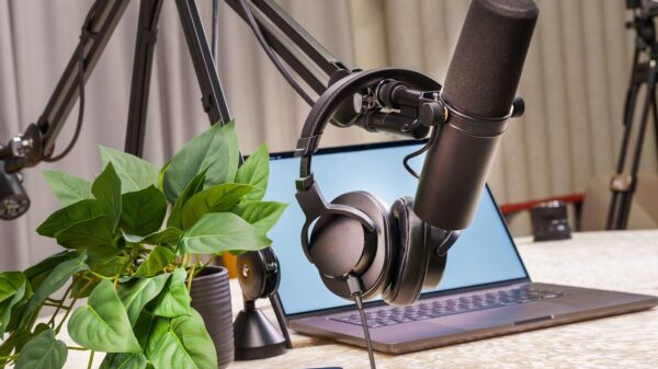 A modern podcast studio setup with a microphone, headphones, and laptop, ideal for media production and online broadcasting.