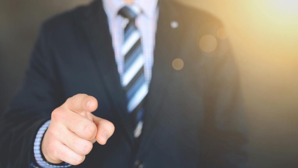 Confident businessman in a suit pointing forward, signifying leadership and focus.