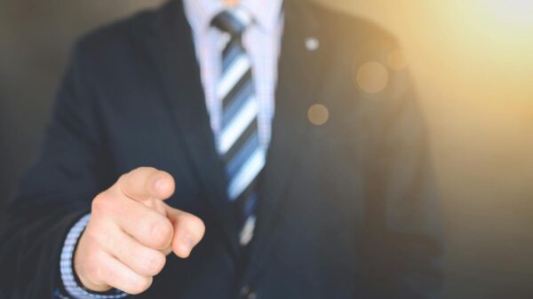 Confident businessman in a suit pointing forward, signifying leadership and focus.