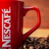 Red mug surrounded by coffee beans creates a cozy and inviting atmosphere.