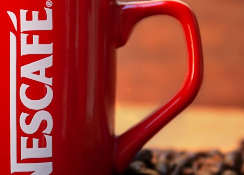 Red mug surrounded by coffee beans creates a cozy and inviting atmosphere.