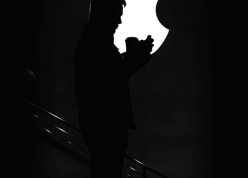 Silhouetted man against bright Apple logo, creating dramatic contrast.