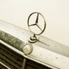 A detailed shot of a classic Mercedes-Benz emblem on a vintage car.