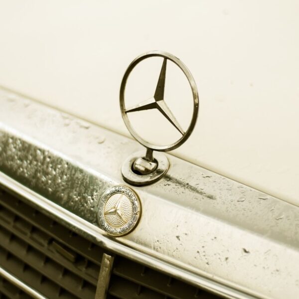 A detailed shot of a classic Mercedes-Benz emblem on a vintage car.