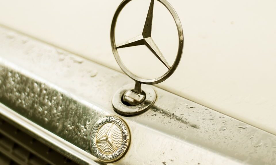 A detailed shot of a classic Mercedes-Benz emblem on a vintage car.