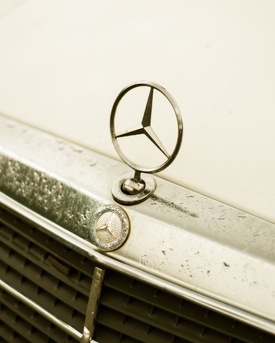 A detailed shot of a classic Mercedes-Benz emblem on a vintage car.