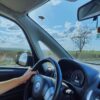 View from inside a car showcasing a scenic drive with blue skies and an open road.