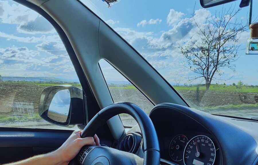View from inside a car showcasing a scenic drive with blue skies and an open road.
