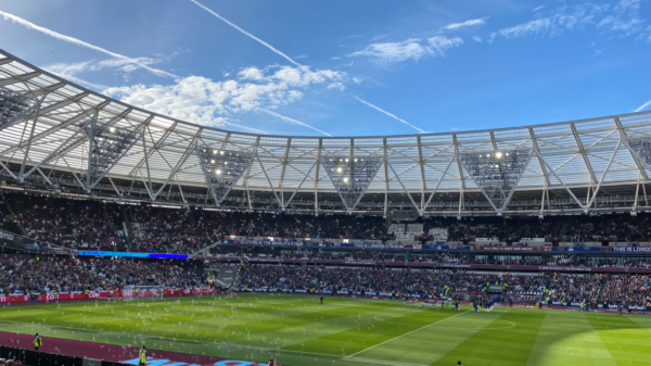 A packed London Stadium hosts a thrilling soccer match, with vibrant atmosphere and engaged crowd.