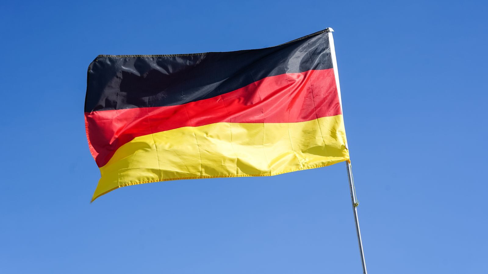 German national flag waving prominently against a bright blue sky in Lüneburg, Germany.