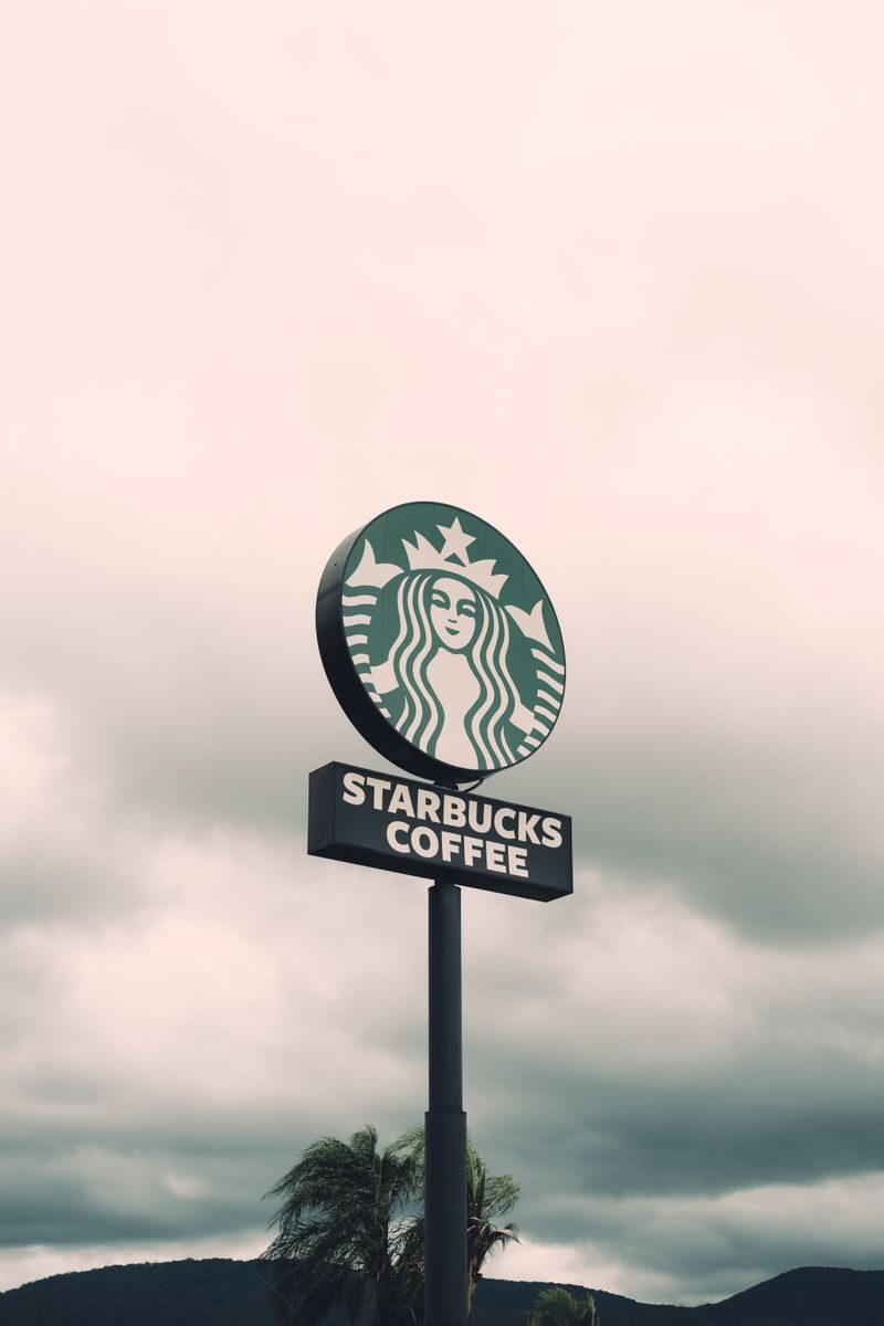 A Starbucks Coffee sign with a cloudy sky backdrop in Brazil, creating a moody ambiance.