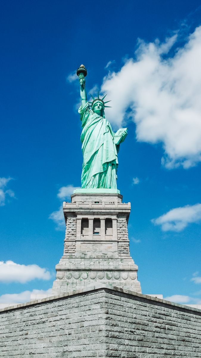 Iconic Statue of Liberty shot with a dramatic low angle against a clear blue sky, perfect for travel and tourism themes.