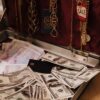 Open suitcase filled with cash, gold necklaces, and a sale tag, symbolizing wealth.