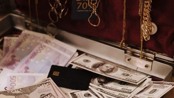 Open suitcase filled with cash, gold necklaces, and a sale tag, symbolizing wealth.