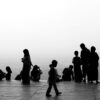 Monochrome silhouettes of people socializing on a scenic observation platform.