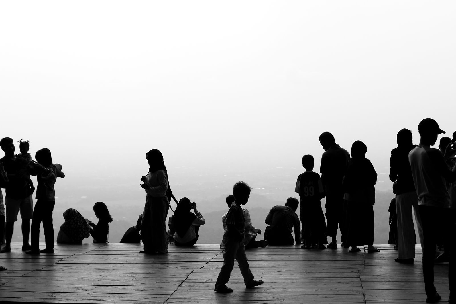 Monochrome silhouettes of people socializing on a scenic observation platform.