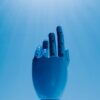 A robotic hand reaching out against a radiant blue sky, symbolizing futuristic technology.