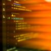 Vibrant, motion-blurred view of programming code on a computer screen with an abstract orange glow.