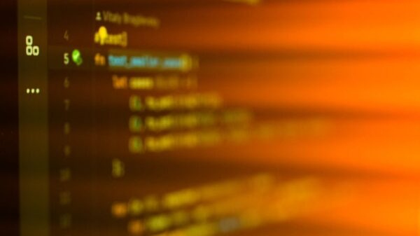 Vibrant, motion-blurred view of programming code on a computer screen with an abstract orange glow.