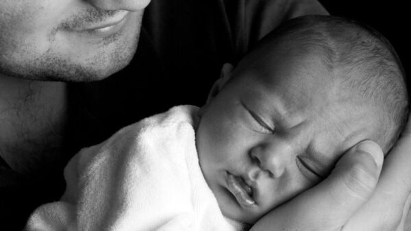 A touching black and white portrait of a father holding his sleeping newborn baby.